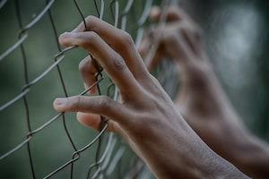 Hands on metal fence