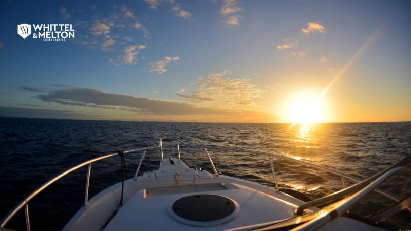 Boat cruising at sunset on open water – Whittel & Melton Injury Lawyers logo in corner.