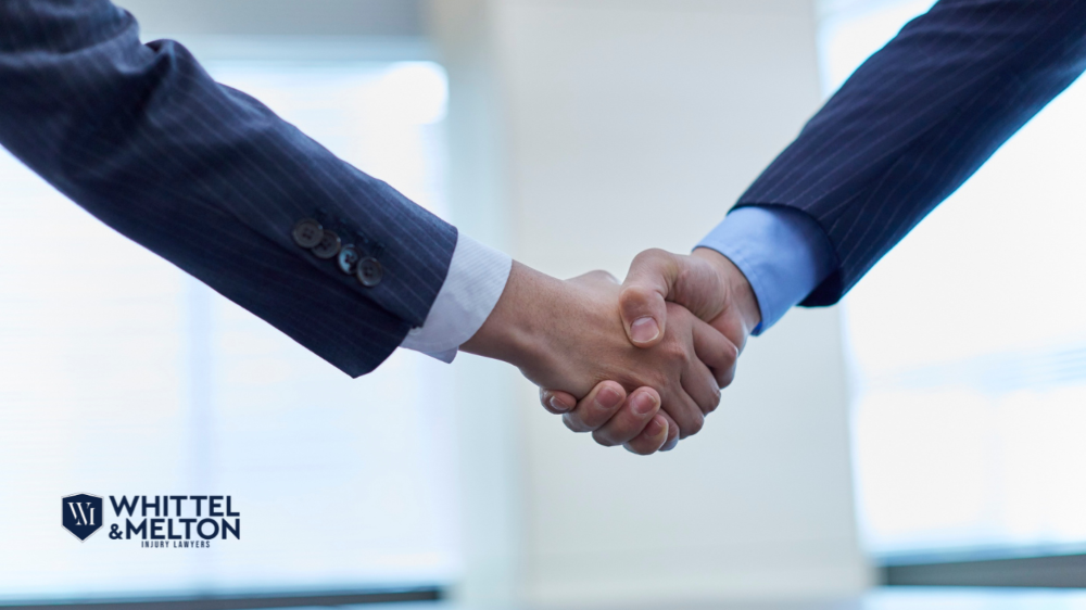 Two professionals in suits shaking hands with the Whittel & Melton Injury Lawyers logo in the corner.